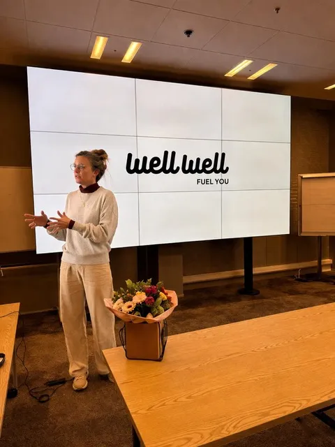 Caroline geeft een workshop voor een scherm met het WellWell-logo